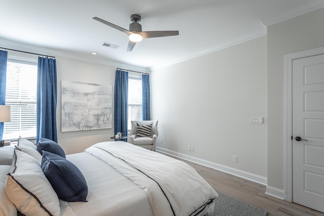 bedroom featuring ornamental molding, multiple windows, and wood finished floors