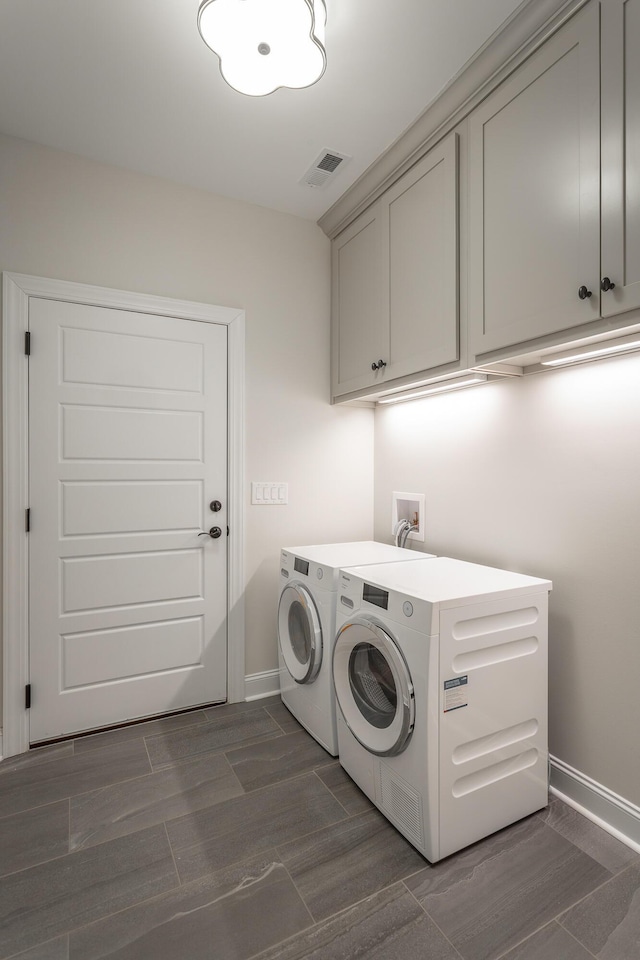 laundry area with separate washer and dryer, cabinet space, visible vents, and baseboards