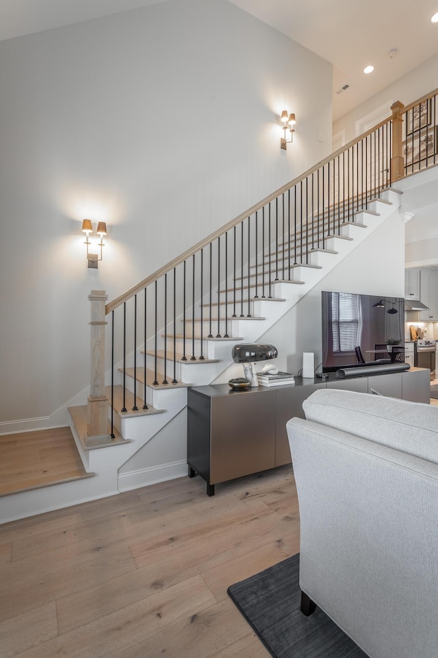 living room with stairs, a high ceiling, and wood finished floors