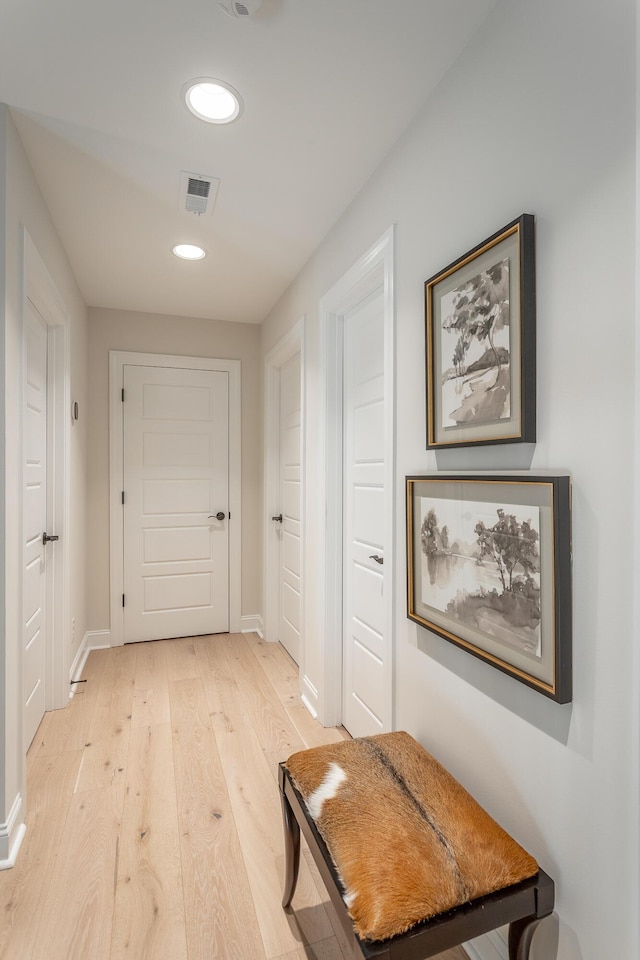 hallway featuring light wood-type flooring, baseboards, visible vents, and recessed lighting