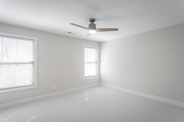 carpeted spare room with baseboards, visible vents, and a ceiling fan