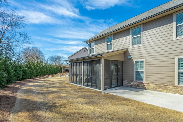 back of property with a sunroom, a yard, and a patio