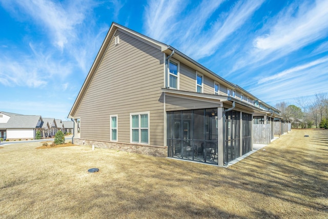 back of house with a yard, brick siding, and a sunroom