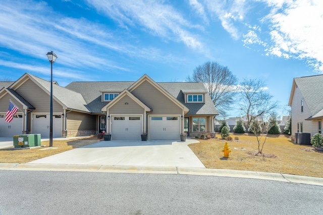 craftsman-style house with concrete driveway, central AC, an attached garage, and roof with shingles