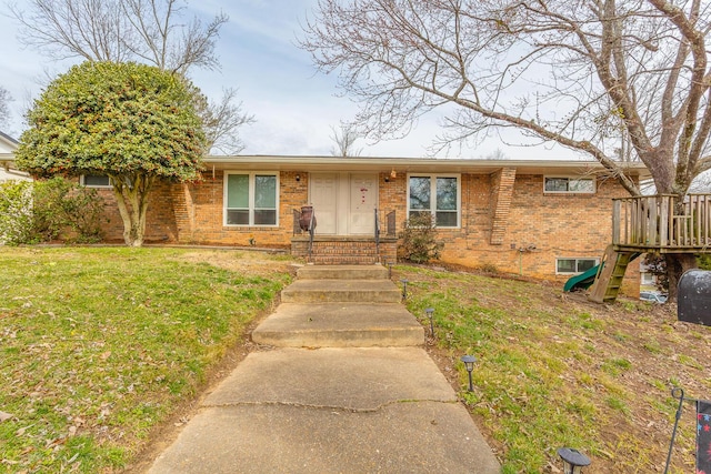 ranch-style house with entry steps, brick siding, a front lawn, and a playground