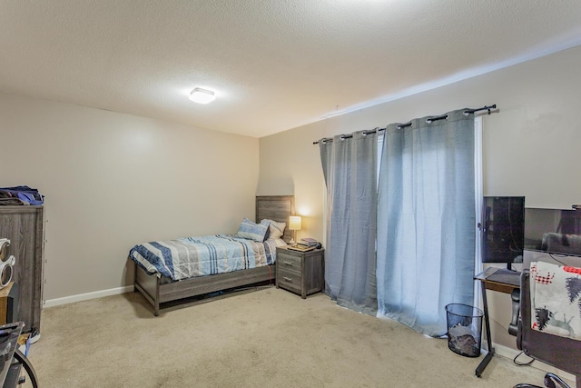 bedroom with light carpet, a textured ceiling, and baseboards