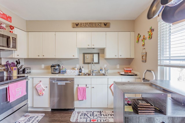 kitchen with a sink, stainless steel appliances, light countertops, and white cabinetry