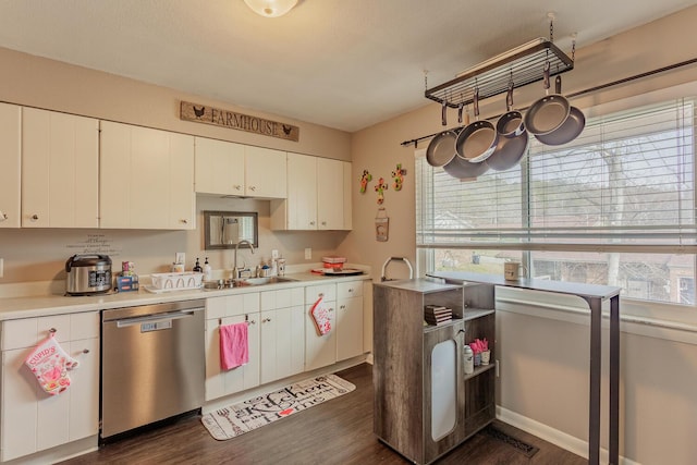 kitchen with a wealth of natural light, dishwasher, light countertops, white cabinetry, and a sink