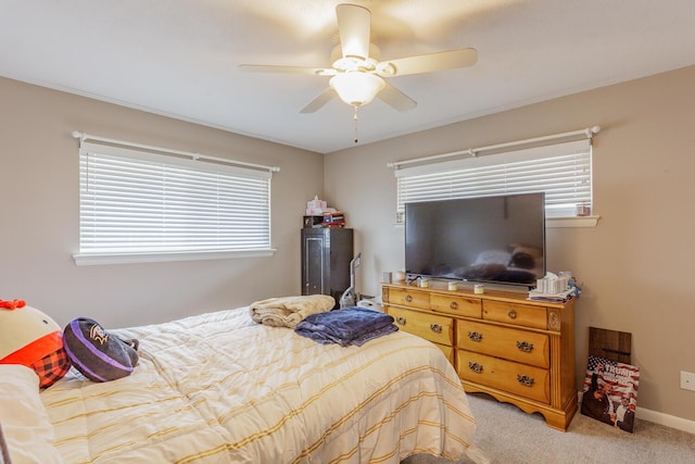 bedroom with baseboards, multiple windows, a ceiling fan, and light colored carpet