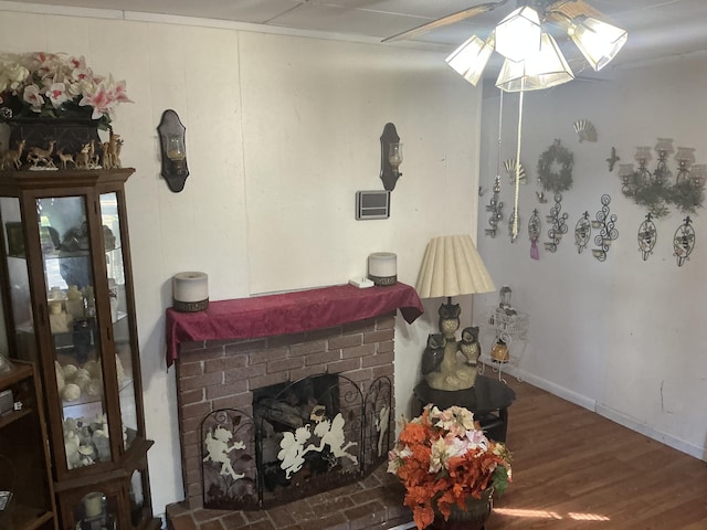 living area featuring a brick fireplace, baseboards, and wood finished floors