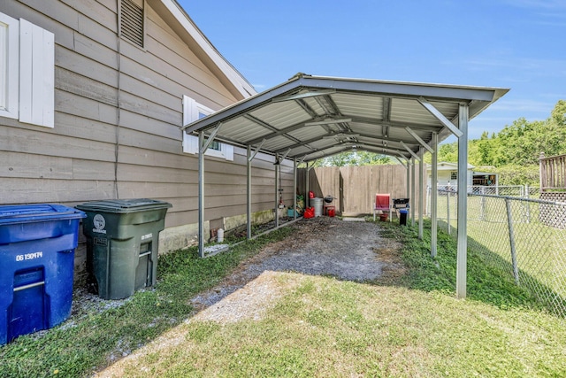 view of parking featuring driveway, fence, and a detached carport