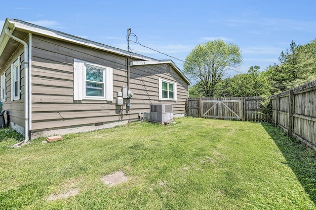 exterior space with central AC unit, a fenced backyard, crawl space, a lawn, and a gate