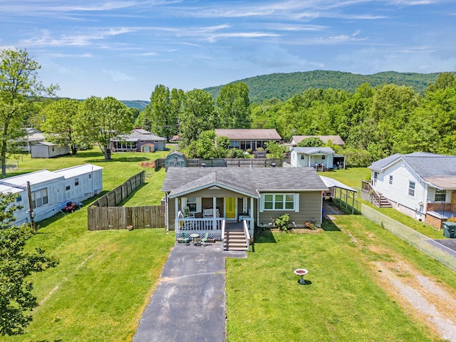 view of front of house with driveway, fence, a porch, and a front yard