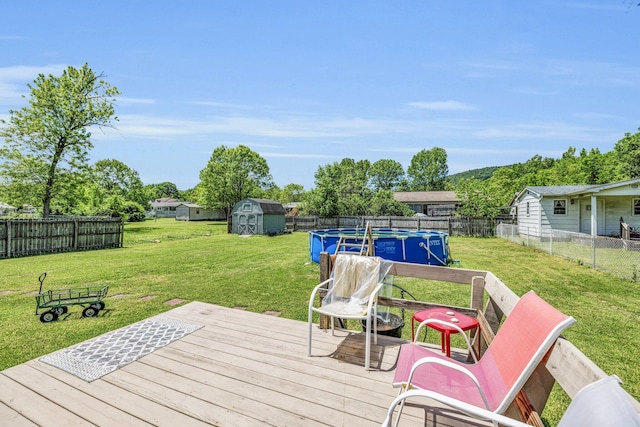 wooden deck featuring a storage shed, a fenced backyard, a lawn, and a fenced in pool