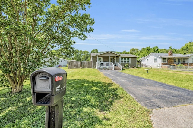 view of front of house featuring a front yard, covered porch, and fence