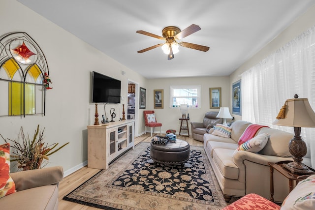 living room featuring baseboards, light wood-style flooring, and a ceiling fan