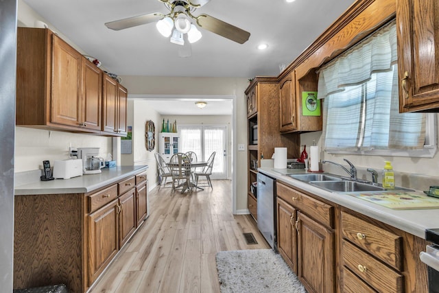 kitchen with brown cabinets, light countertops, a sink, and stainless steel dishwasher