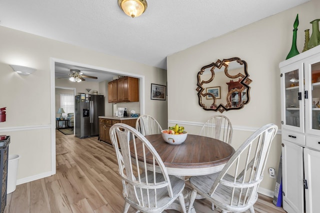 dining space with a textured ceiling, ceiling fan, and light wood-style floors