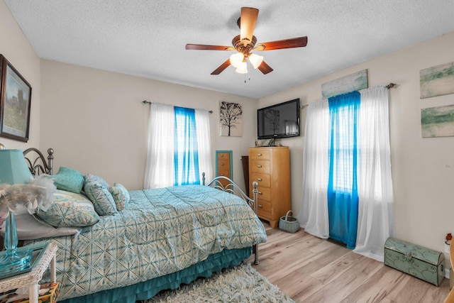 bedroom with light wood-style flooring, a ceiling fan, and a textured ceiling