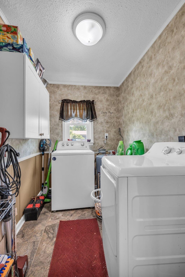 laundry area with cabinet space, washer and clothes dryer, and a textured ceiling