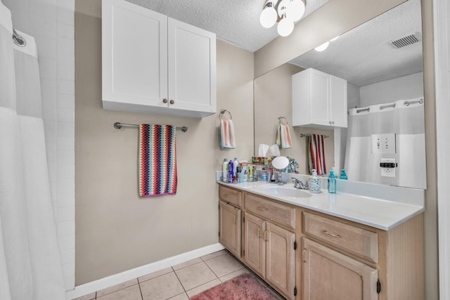 bathroom with a textured ceiling, vanity, baseboards, visible vents, and tile patterned floors