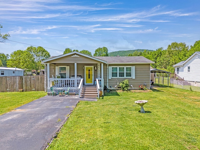 view of front of home featuring covered porch, driveway, a front lawn, and fence