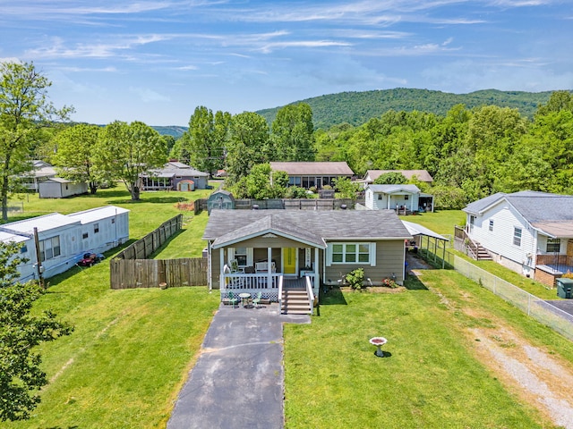 view of front of property featuring a porch, a front yard, driveway, and fence