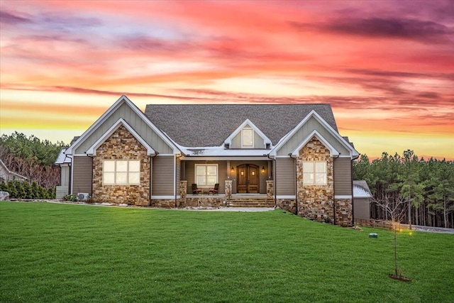 view of front facade featuring stone siding, a yard, and board and batten siding