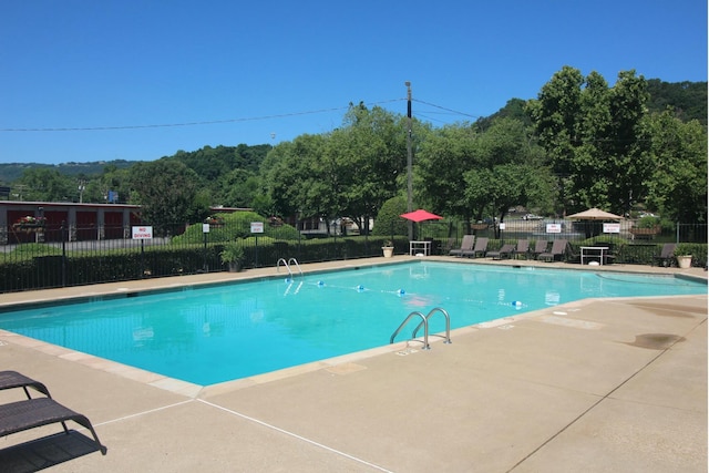 community pool with a patio area and fence