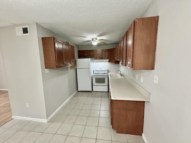 kitchen with white appliances, visible vents, light countertops, a sink, and light tile patterned flooring