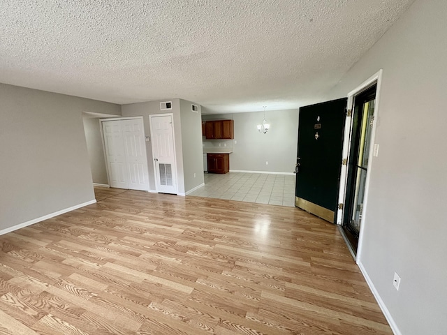 unfurnished room with visible vents, baseboards, a textured ceiling, and light wood finished floors