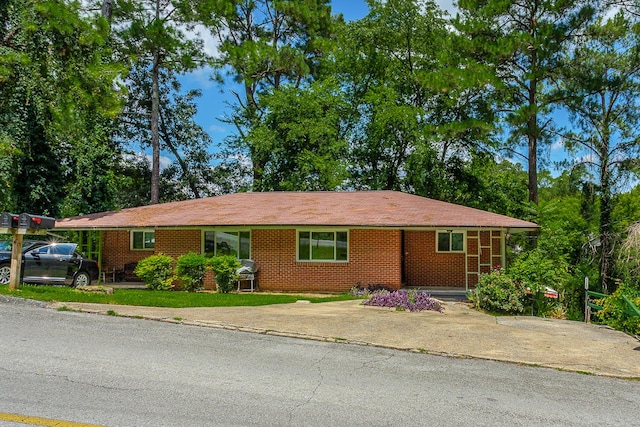 single story home featuring driveway, a front yard, and brick siding