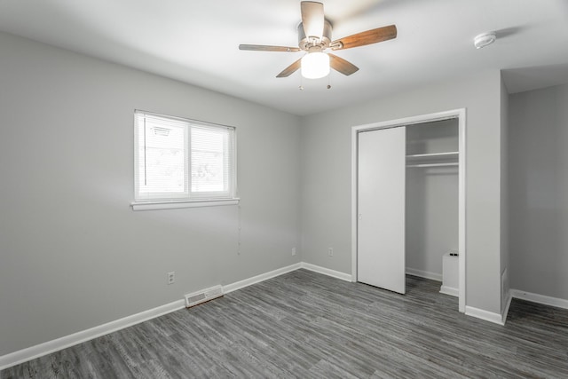 unfurnished bedroom featuring a closet, visible vents, a ceiling fan, wood finished floors, and baseboards