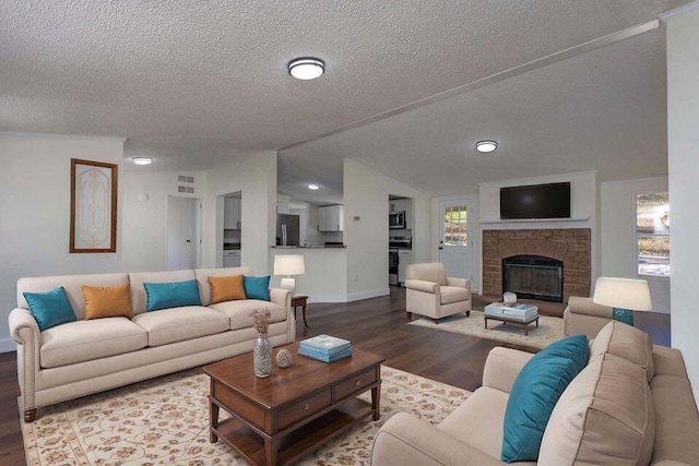 living room featuring a fireplace, lofted ceiling, a textured ceiling, wood finished floors, and baseboards