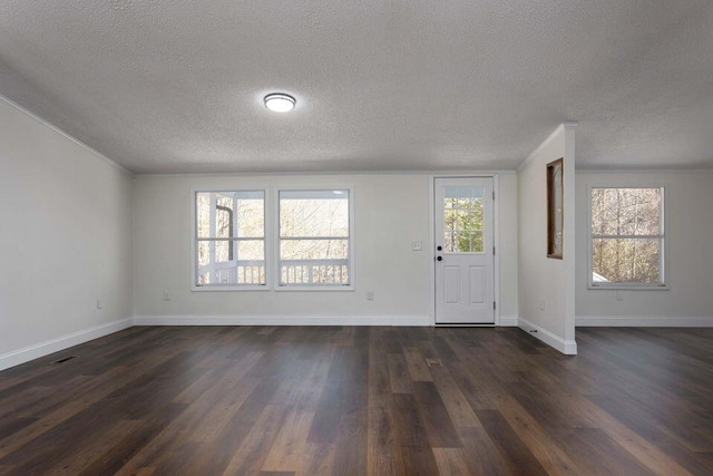 entryway with dark wood-type flooring, a wealth of natural light, a textured ceiling, and baseboards