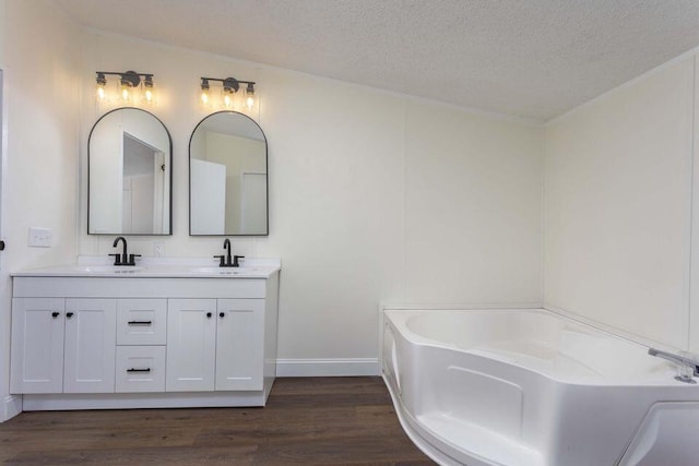 bathroom featuring a sink, a textured ceiling, a bath, and wood finished floors