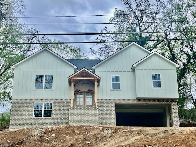 view of front of property with board and batten siding, brick siding, and a garage