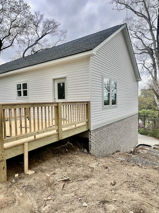 rear view of property featuring a shingled roof and a deck