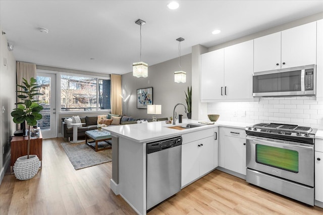 kitchen with decorative backsplash, stainless steel appliances, a sink, and light countertops