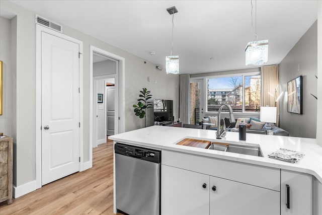 kitchen featuring light wood finished floors, light countertops, visible vents, a sink, and dishwasher