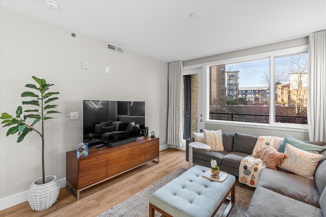 living room with light wood-style floors, baseboards, and visible vents