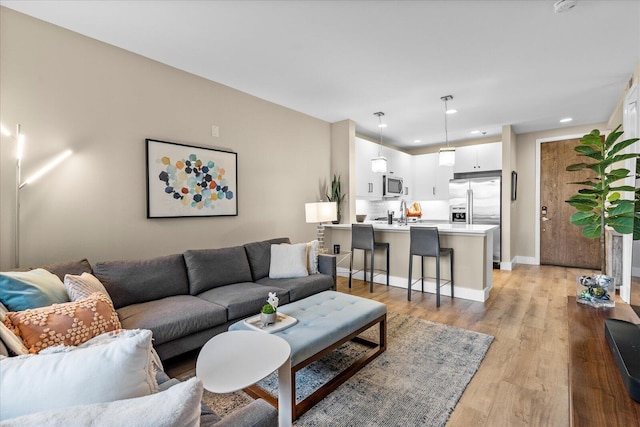 living area featuring recessed lighting, light wood-style flooring, and baseboards