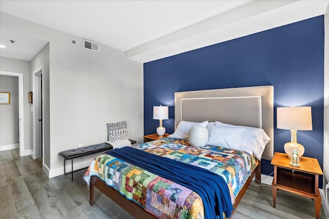 bedroom with visible vents, baseboards, and wood finished floors