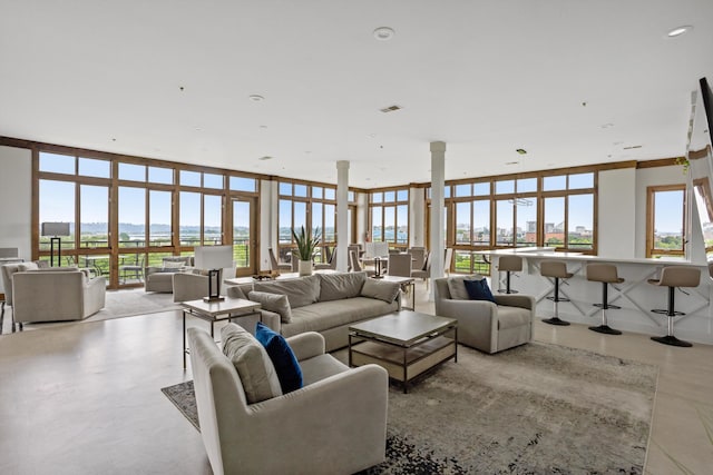 living room with expansive windows, visible vents, decorative columns, and recessed lighting