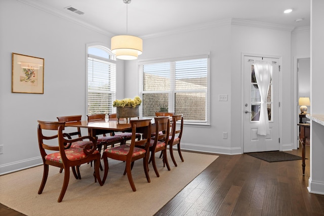 dining room featuring dark wood-type flooring, visible vents, ornamental molding, and baseboards