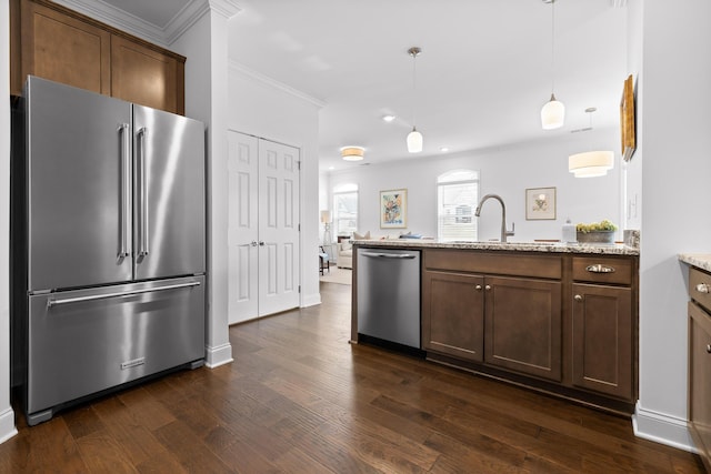 kitchen featuring appliances with stainless steel finishes, a sink, dark wood finished floors, and light stone countertops