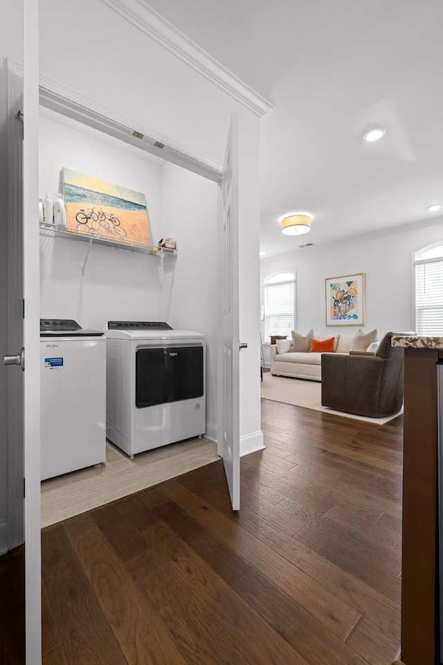 laundry room with a wealth of natural light, washing machine and dryer, laundry area, and wood finished floors