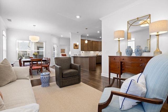 living room with a healthy amount of sunlight, dark wood-style floors, ornamental molding, and recessed lighting