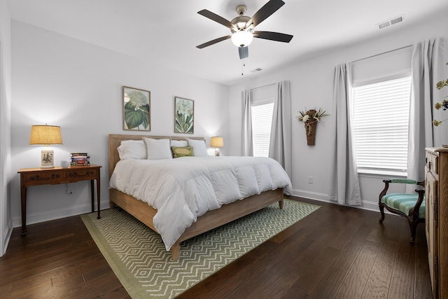 bedroom featuring dark wood-type flooring, visible vents, baseboards, and a ceiling fan