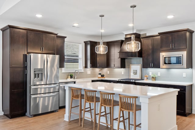 kitchen featuring stainless steel appliances, a kitchen island, hanging light fixtures, light countertops, and custom exhaust hood